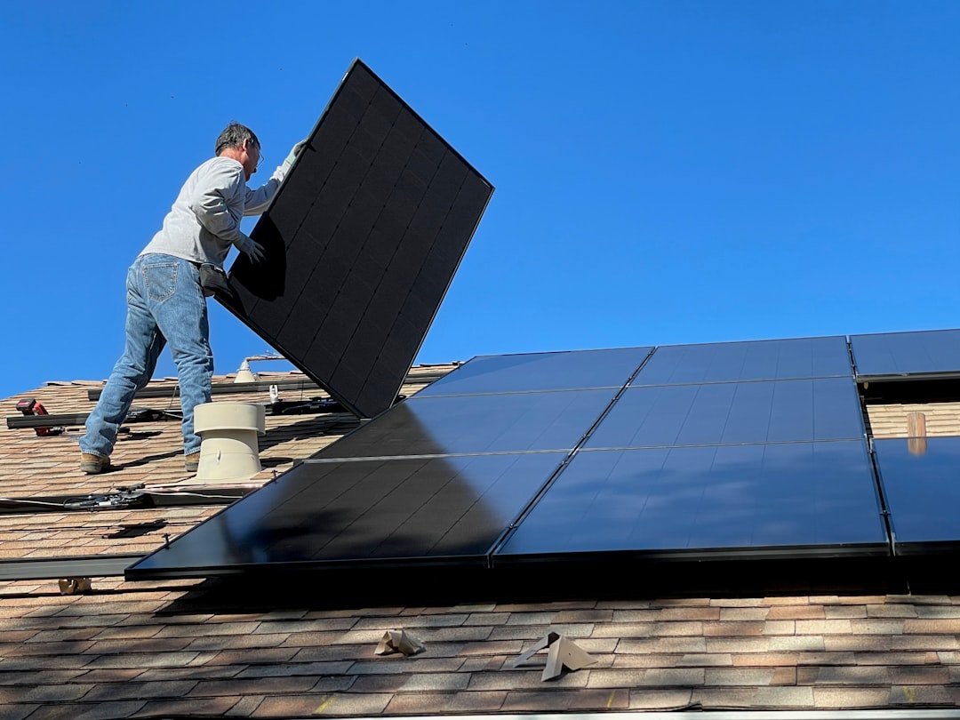 Homme assis sur un panneau solaire illustrant un devis pour installation de panneaux solaires
