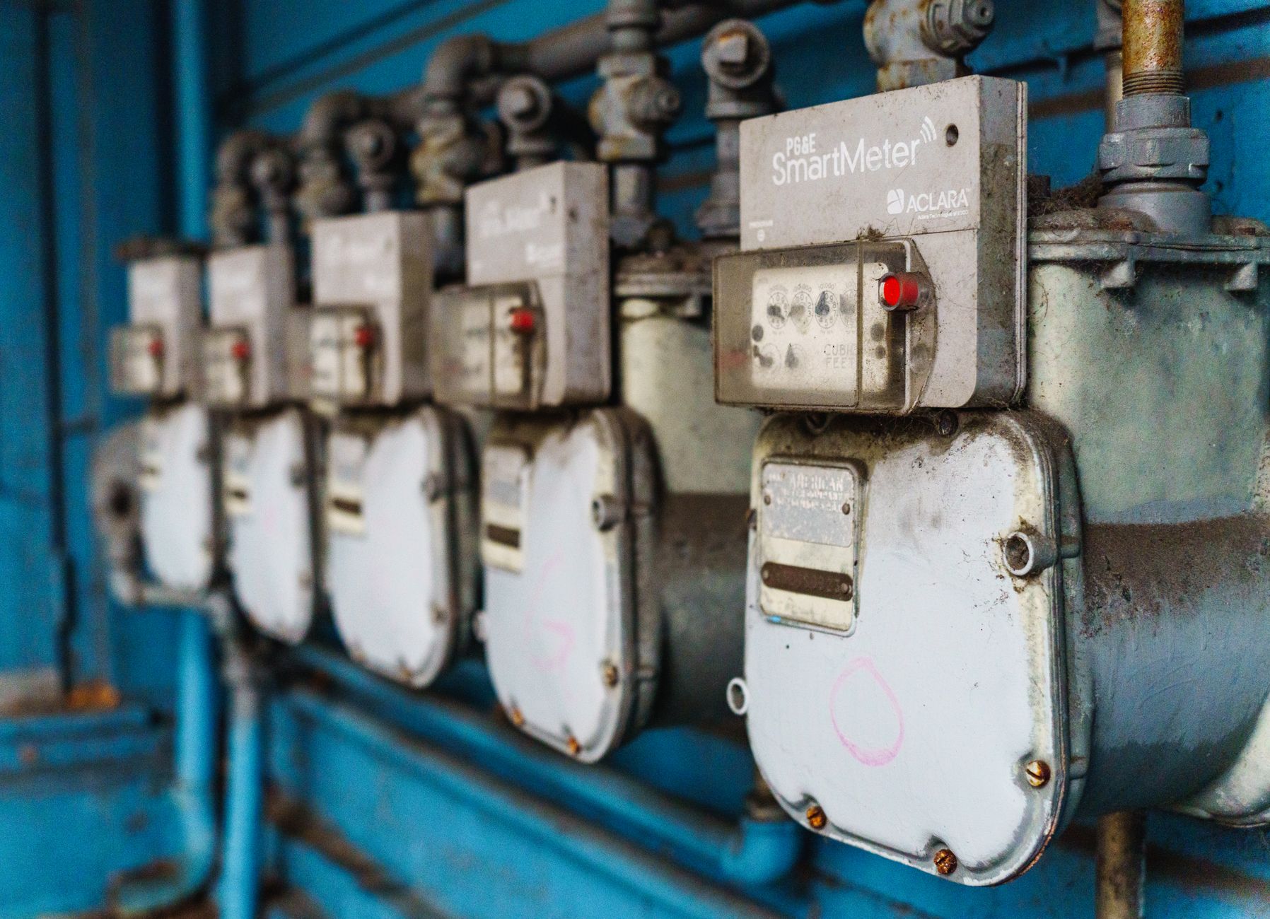 Compteurs intelligents alignés sur un mur industriel bleu - Guide pour lire sa facture d'électricité
